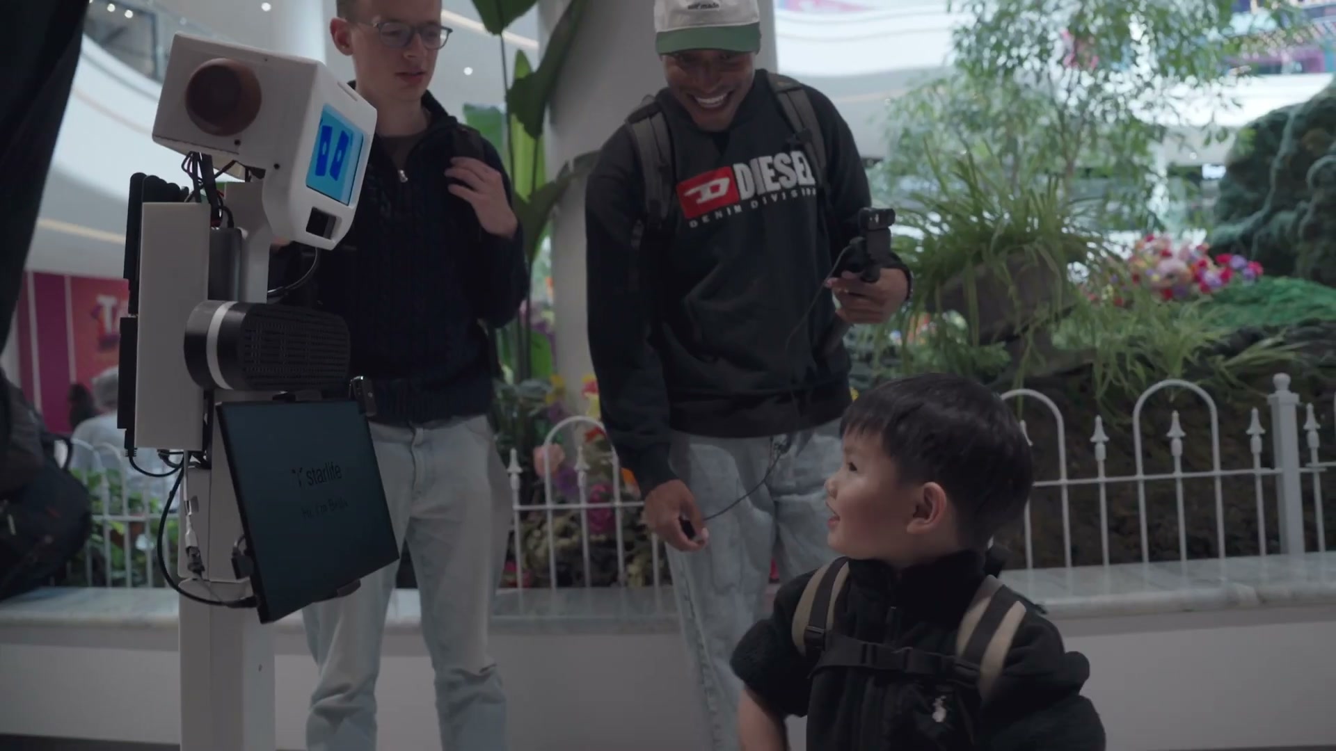 A remote pilot greeting a child through the robot on the mall floor